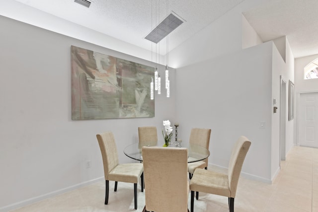 tiled dining space with lofted ceiling and a textured ceiling