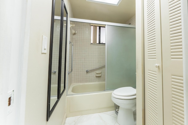 bathroom with toilet and shower / bath combination with glass door