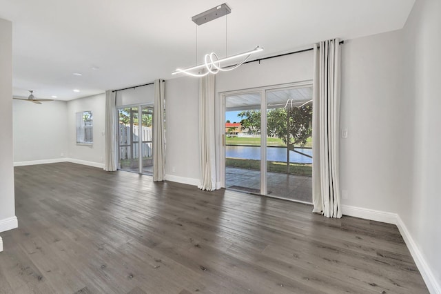 interior space featuring ceiling fan, dark hardwood / wood-style flooring, and a water view