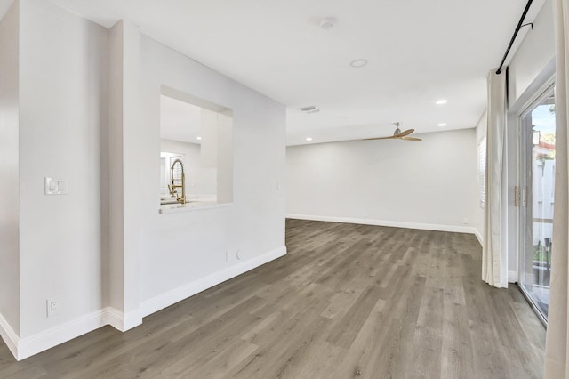 spare room with sink, ceiling fan, and hardwood / wood-style floors