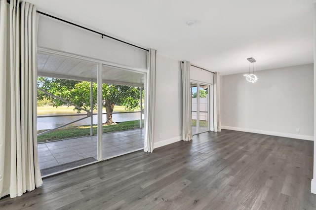 spare room featuring a water view and dark hardwood / wood-style floors