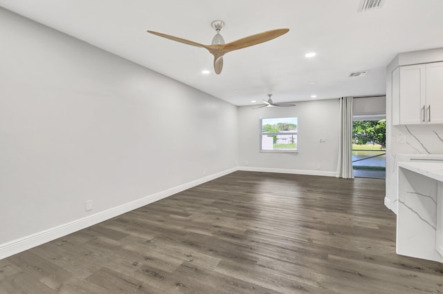 unfurnished living room with ceiling fan and dark wood-type flooring