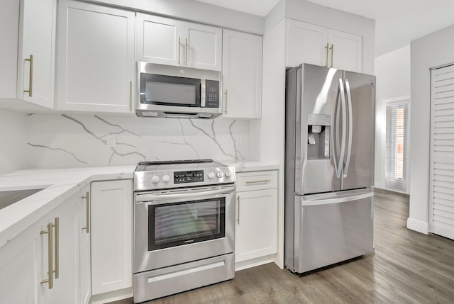 kitchen with appliances with stainless steel finishes, white cabinetry, and backsplash