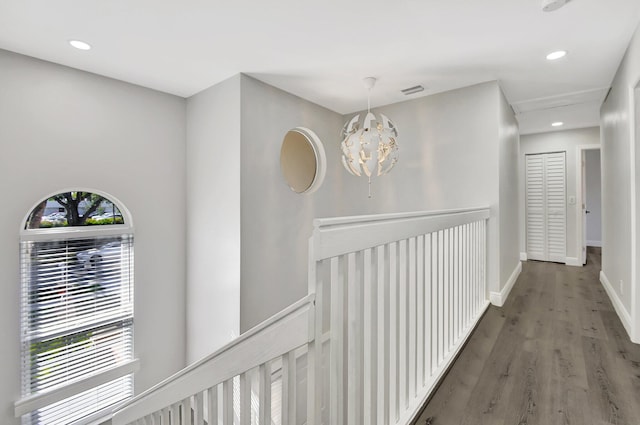 corridor featuring hardwood / wood-style flooring, a notable chandelier, and a wealth of natural light