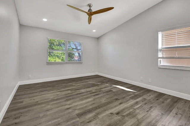 spare room featuring lofted ceiling, ceiling fan, a healthy amount of sunlight, and dark wood-type flooring