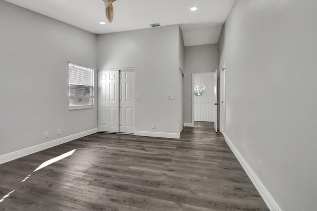 interior space featuring ceiling fan, dark wood-type flooring, and a towering ceiling