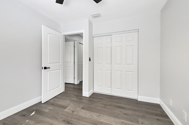 unfurnished bedroom with ceiling fan, dark hardwood / wood-style flooring, and a closet