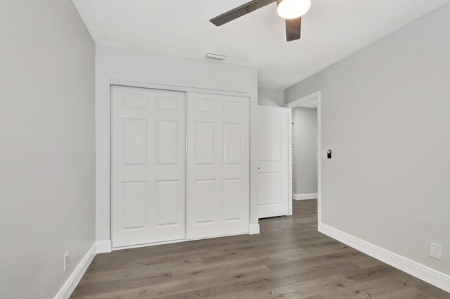 unfurnished bedroom with ceiling fan, dark wood-type flooring, and a closet