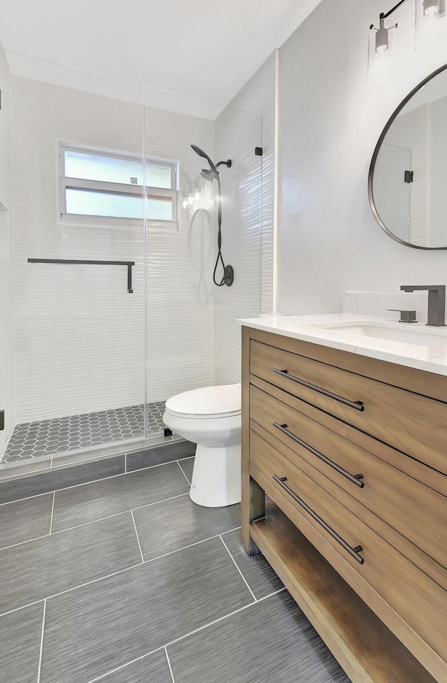 bathroom with a shower with door, vanity, and toilet