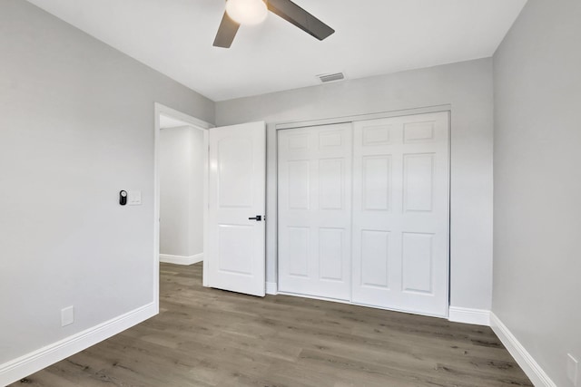 unfurnished bedroom with ceiling fan, dark wood-type flooring, and a closet