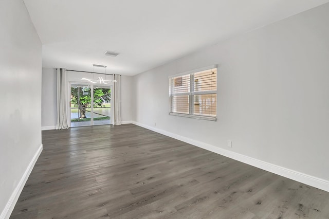 empty room with dark wood-type flooring and plenty of natural light