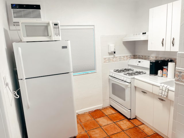 kitchen with custom exhaust hood, white appliances, white cabinets, tile counters, and a wall unit AC