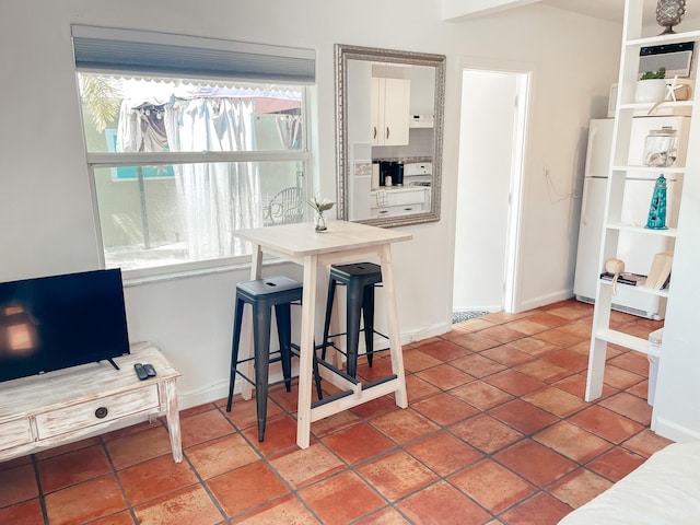 kitchen with a breakfast bar area, white cabinets, and white refrigerator