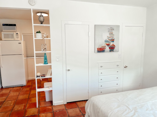 tiled bedroom with white fridge and an AC wall unit