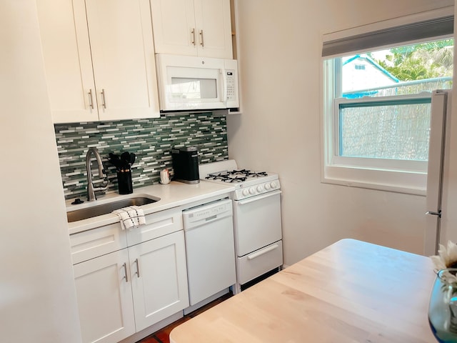 kitchen featuring tasteful backsplash, white cabinetry, sink, and white appliances