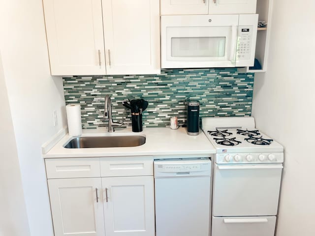 kitchen with white cabinets, decorative backsplash, white appliances, and sink