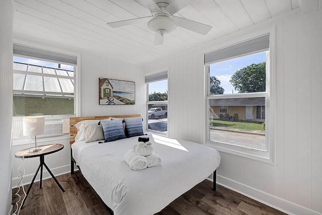 bedroom with wood walls, ceiling fan, and dark hardwood / wood-style floors