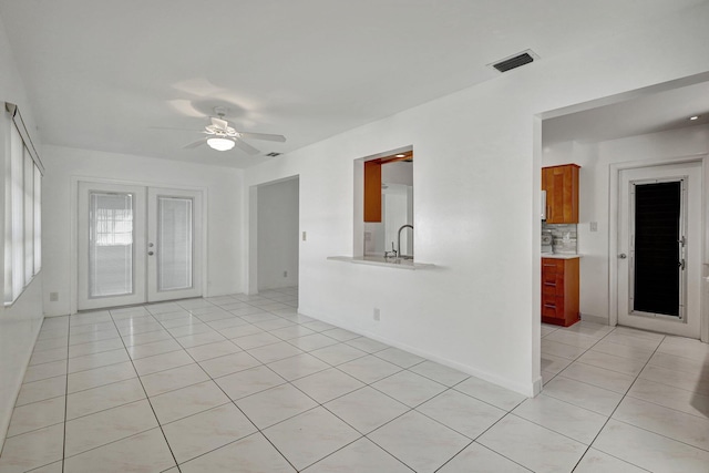 unfurnished living room with ceiling fan, french doors, light tile patterned flooring, and sink