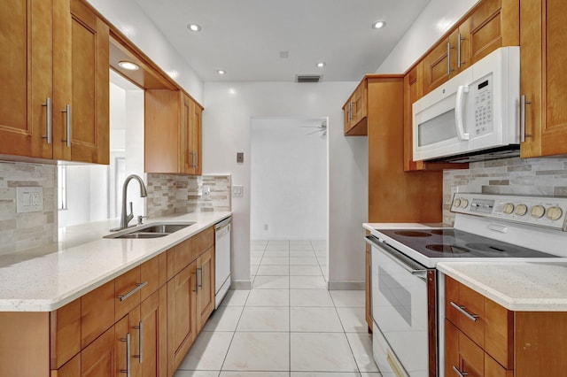 kitchen with light stone countertops, decorative backsplash, white appliances, sink, and light tile patterned floors