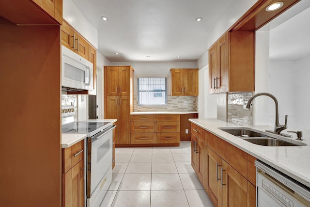 kitchen featuring light stone countertops, tasteful backsplash, white appliances, sink, and light tile patterned flooring