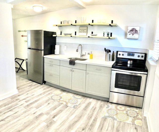 kitchen featuring appliances with stainless steel finishes, backsplash, gray cabinetry, sink, and light hardwood / wood-style flooring