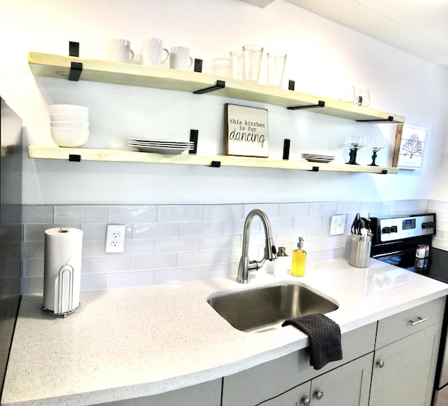 kitchen featuring electric range, tasteful backsplash, and sink