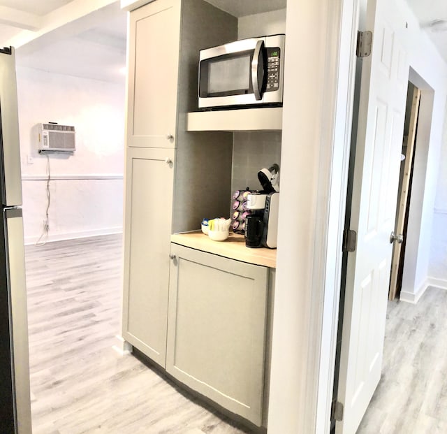 hall with an AC wall unit and light hardwood / wood-style floors