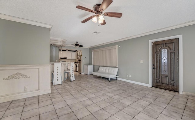 tiled entryway with ceiling fan, ornamental molding, and a textured ceiling