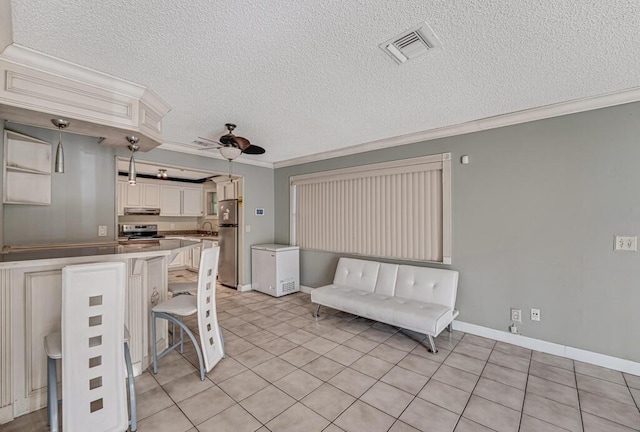 kitchen featuring appliances with stainless steel finishes, hanging light fixtures, ornamental molding, ceiling fan, and light tile patterned floors