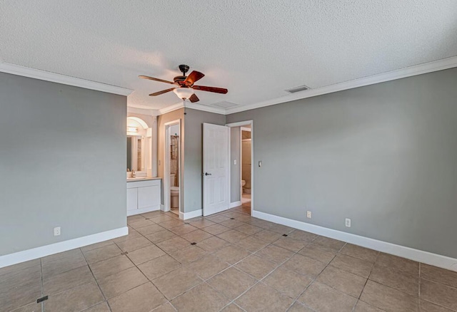 unfurnished bedroom featuring ceiling fan, crown molding, ensuite bathroom, and a textured ceiling