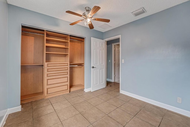 unfurnished bedroom with a textured ceiling, ceiling fan, light tile patterned floors, and a closet