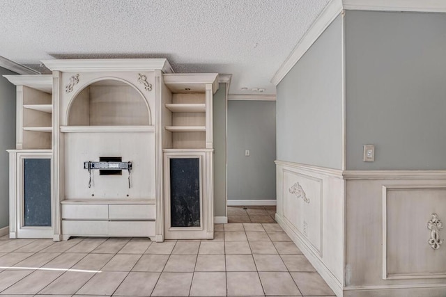 unfurnished living room with built in shelves, light tile patterned floors, ornamental molding, and a textured ceiling