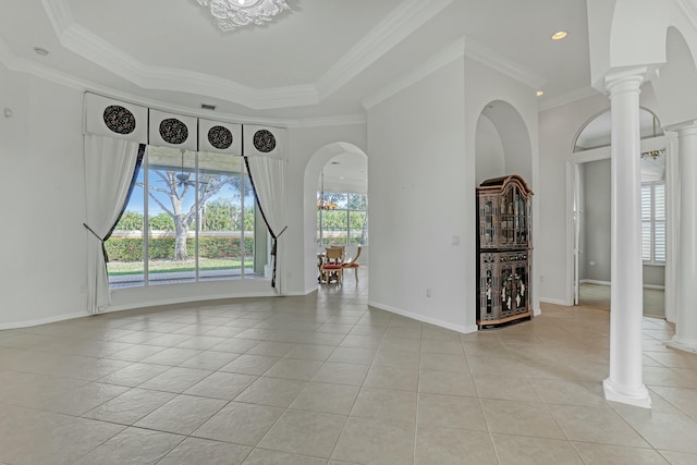 spare room with a tray ceiling, crown molding, decorative columns, and light tile patterned floors