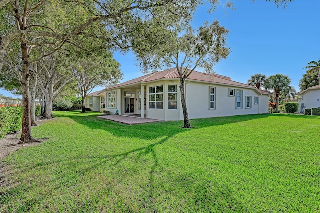 back of property with a yard and a patio