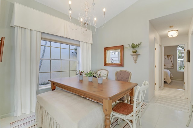 tiled dining space featuring vaulted ceiling, a wealth of natural light, and a notable chandelier