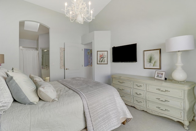 carpeted bedroom featuring a chandelier, vaulted ceiling, and ensuite bath