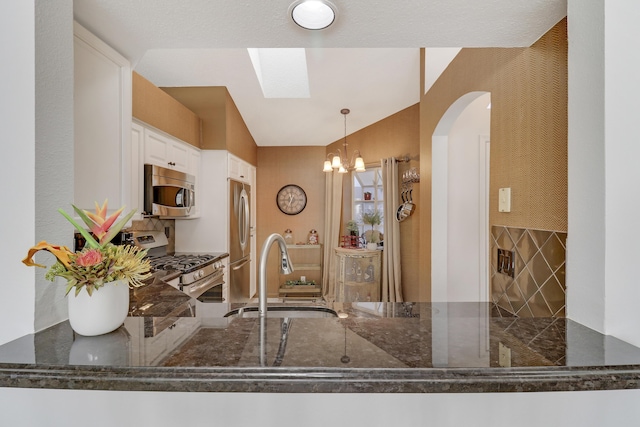 kitchen featuring white cabinets, hanging light fixtures, sink, a skylight, and appliances with stainless steel finishes