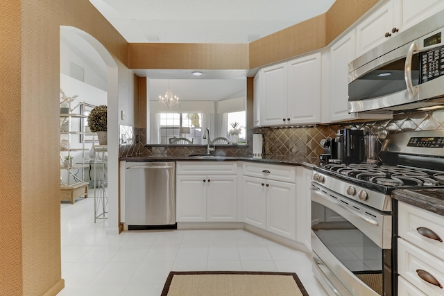 kitchen with decorative backsplash, stainless steel appliances, sink, white cabinetry, and hanging light fixtures