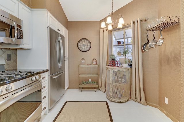 kitchen featuring appliances with stainless steel finishes, backsplash, a chandelier, white cabinetry, and hanging light fixtures