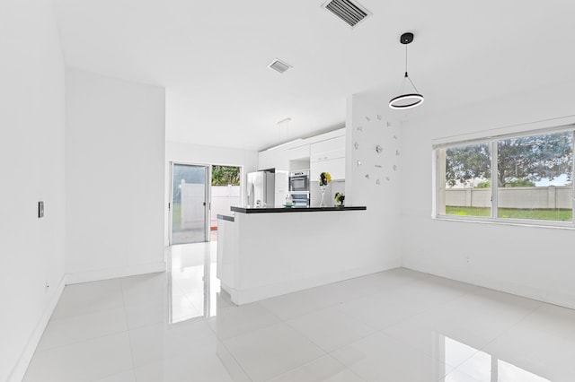 kitchen featuring white cabinets, decorative light fixtures, kitchen peninsula, light tile patterned flooring, and fridge