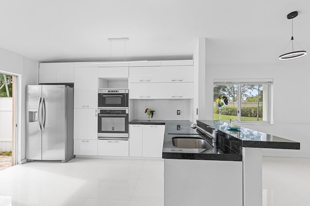 kitchen with white cabinetry, kitchen peninsula, appliances with stainless steel finishes, pendant lighting, and sink