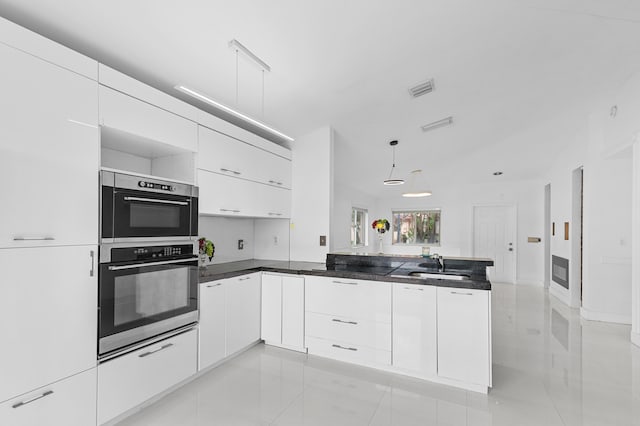 kitchen with decorative light fixtures, sink, white cabinetry, and kitchen peninsula