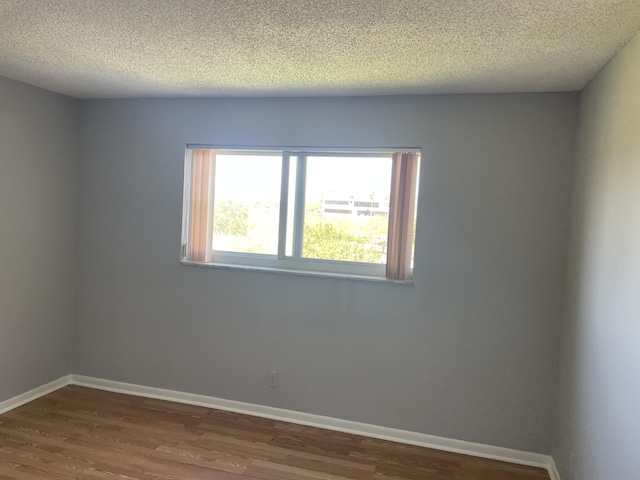 spare room featuring wood finished floors and baseboards