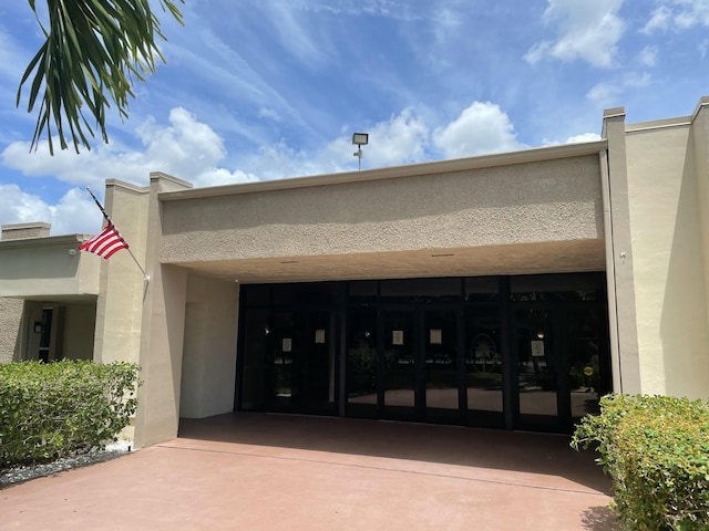 entrance to property featuring driveway, an attached garage, and stucco siding