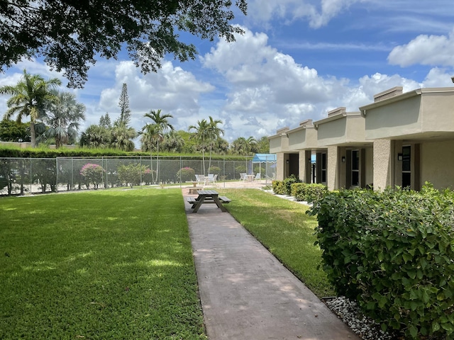 view of property's community featuring fence and a yard