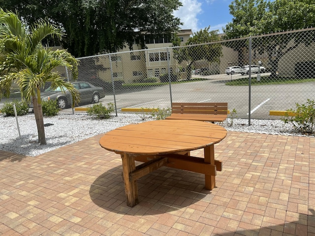 view of property's community featuring fence, outdoor dining area, and a patio