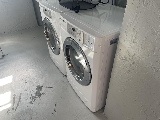 laundry area featuring laundry area, a textured wall, and independent washer and dryer