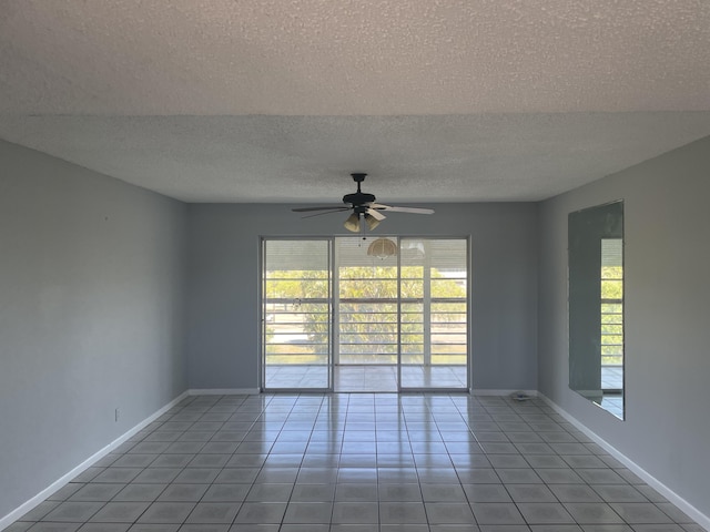 spare room with ceiling fan, plenty of natural light, tile patterned floors, and baseboards