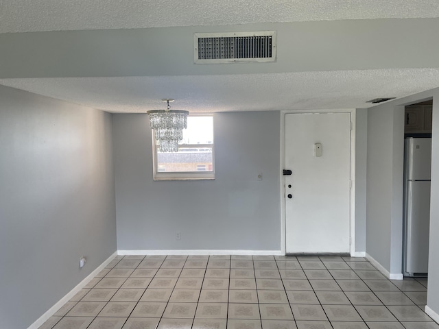 unfurnished room with visible vents, a textured ceiling, and light tile patterned floors