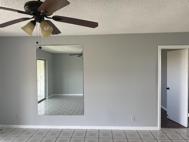 tiled spare room featuring ceiling fan, baseboards, and a textured ceiling